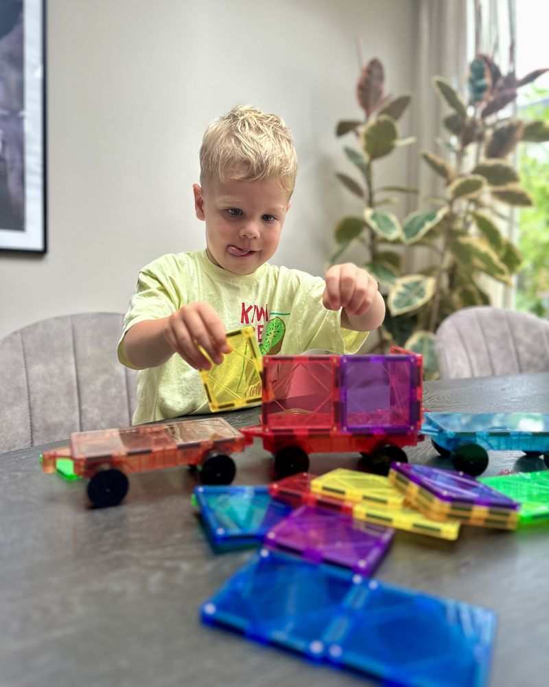 Jongen bouwt met veel magnetische tegels aan tafel