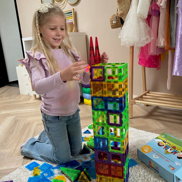 Meisje bouwt een hoge toren van magnetische tegels